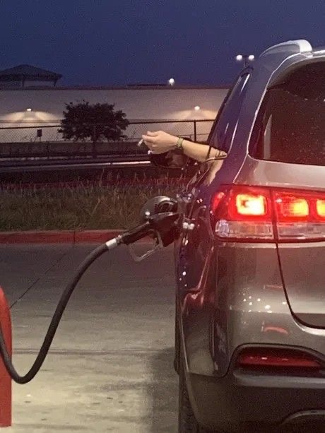 Person Smokes a Cigarette While Filling Up Gasoline
