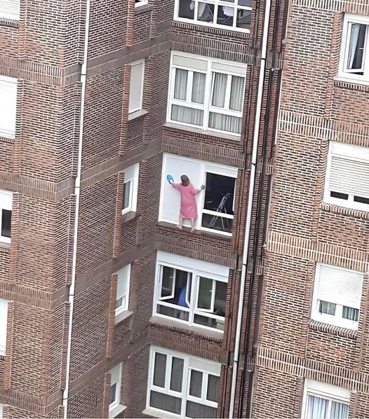 Lady Standing on a Ledge to Clean Her Window