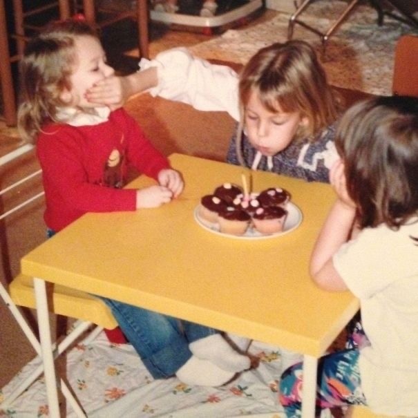 Kid Blowing Candles and Blocking Her Sister