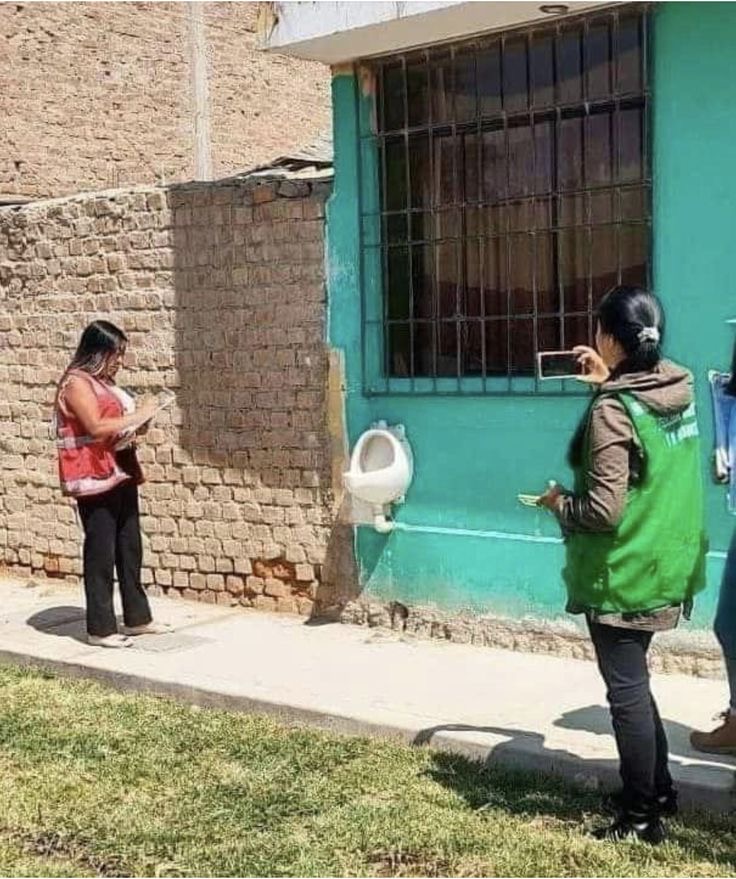 Women Photogra﻿phing a Urinal on the Sidewalk