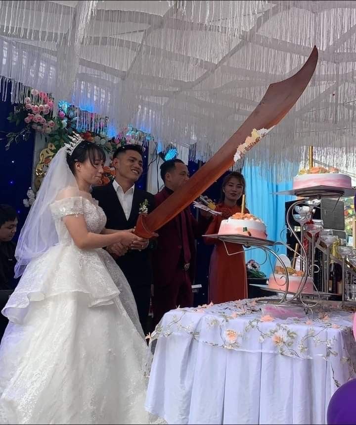 Newlyweds Cutting Their Wedding Cake With a Giant Sword