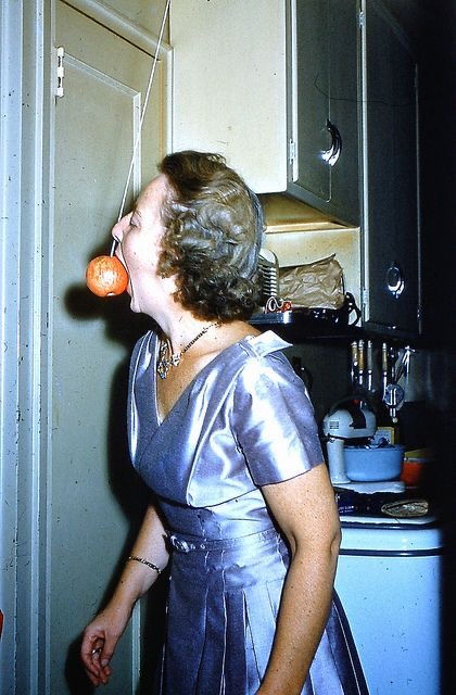 Woman Biting an Apple Hanging From the Ceiling