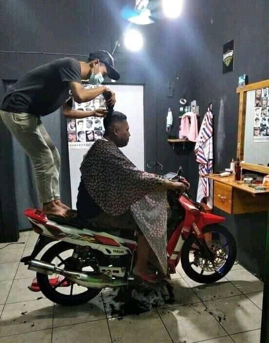 Man Getting a Haircut While Sitting on a Motorcycle