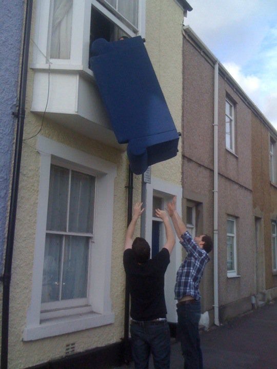 Dudes Wait on the Street for a Sofa Coming Through a Window