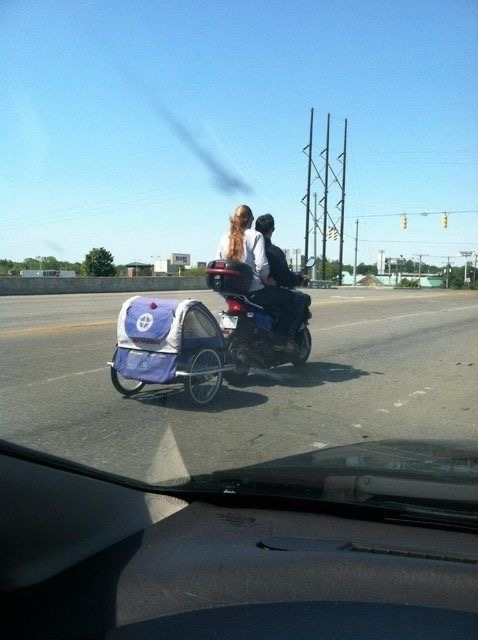 Parents Ride a Motorcycle with Their Child in a Rear Compartment