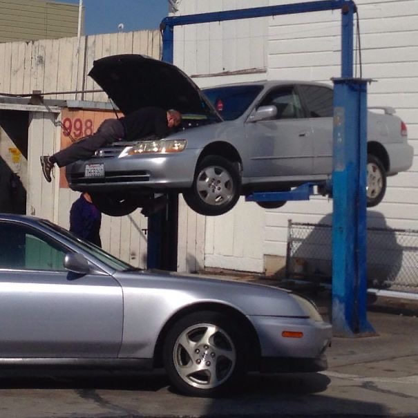 Man Lies on Top of a Car Lifted in the Air