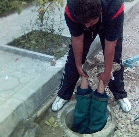 Friend Holding Another Friend in a Street Hole