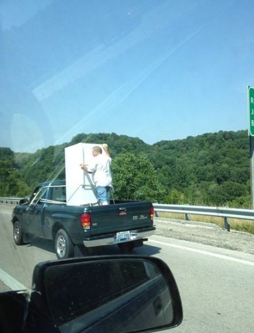 Man Standing in a Truck Holding the Refrigerator