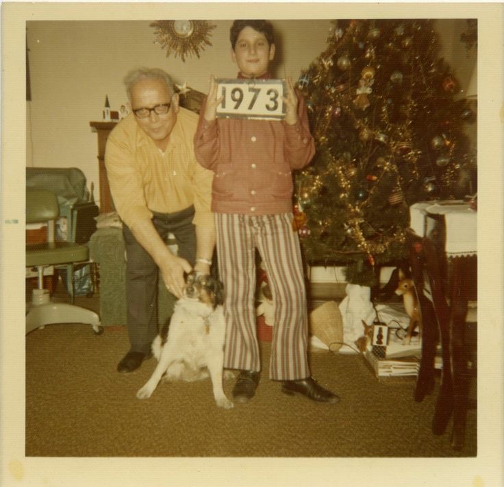 Boy Holding a “1973” Sign While Grandpa Holds the Dog