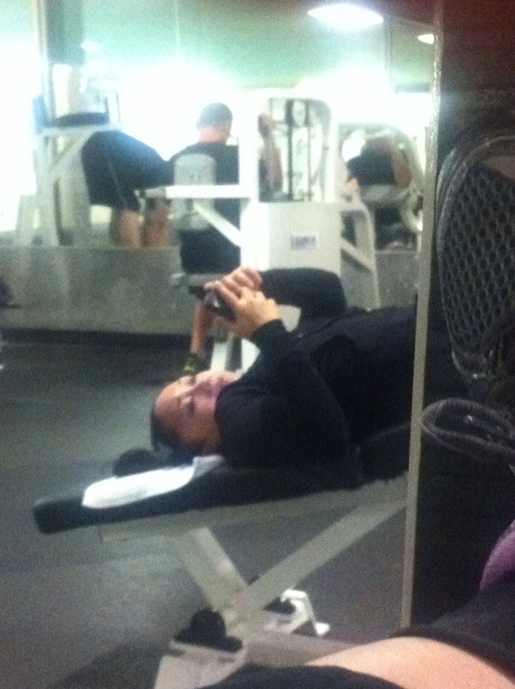 Woman Lying Down at the Gym Using Her Phone