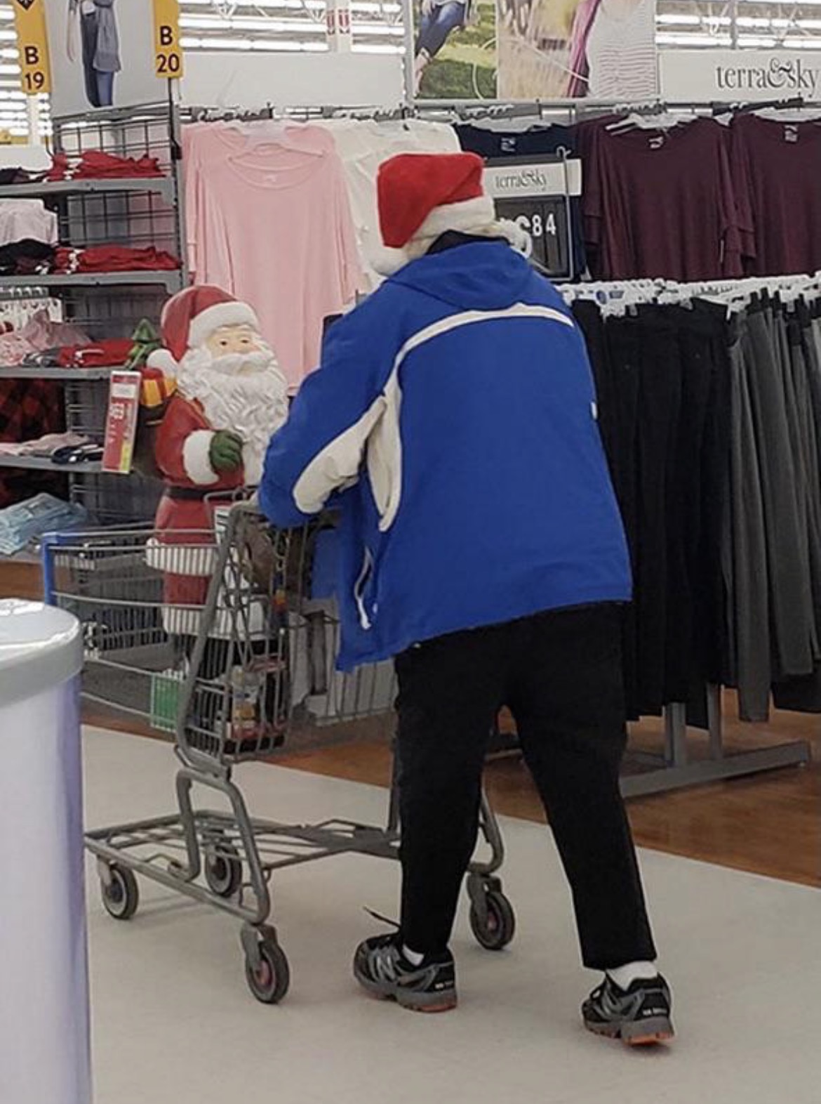 Man Carrying a Santa Doll While Wearing a Christmas Hat
