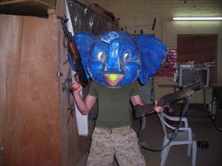 marine wearing fiberglass elephant head from what used to be probably iraqs only amusement park, armed with ak-47 and m-79 grenade launcher