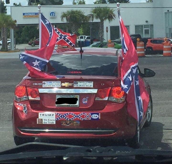 Late model Chevrolet with confederate flags and bumper stickers all over it .