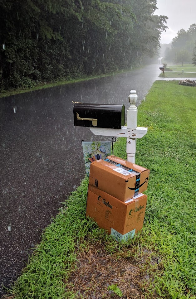 Mailbox with Amazon deliveries place next to it right in the pouring rain.