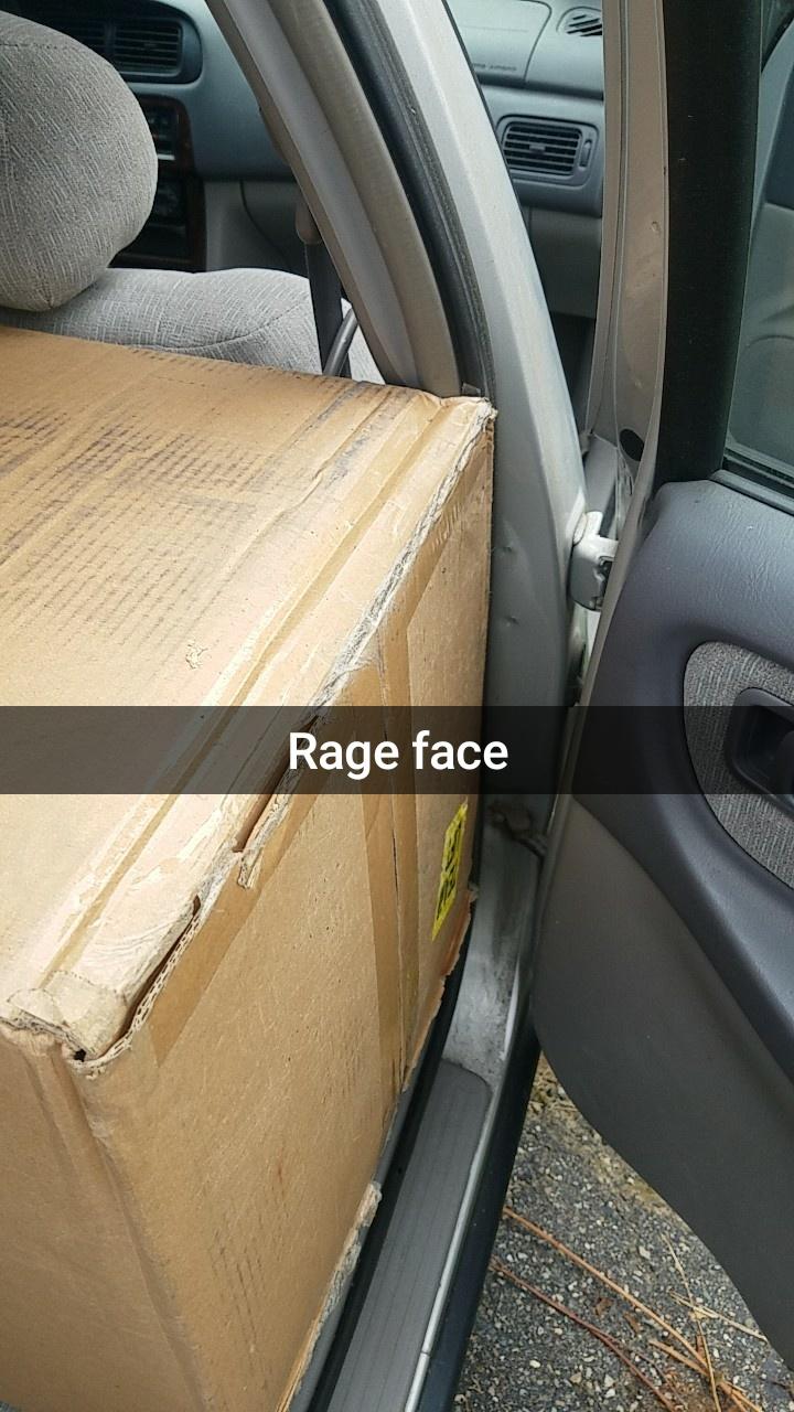 Snapchat of rage face of a box that is just an inch to big to fit in the car.