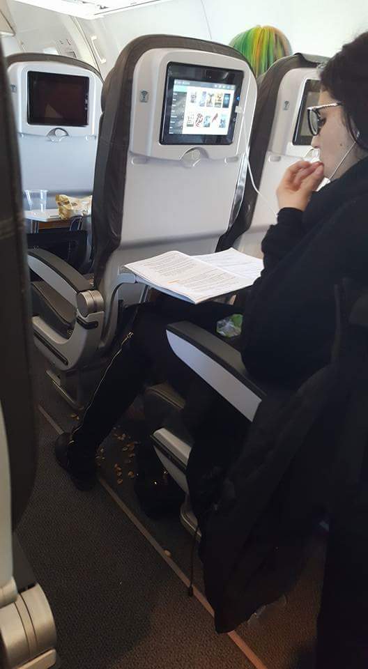 woman eating pistacio nuts on an airplane and throwing the shells on the ground