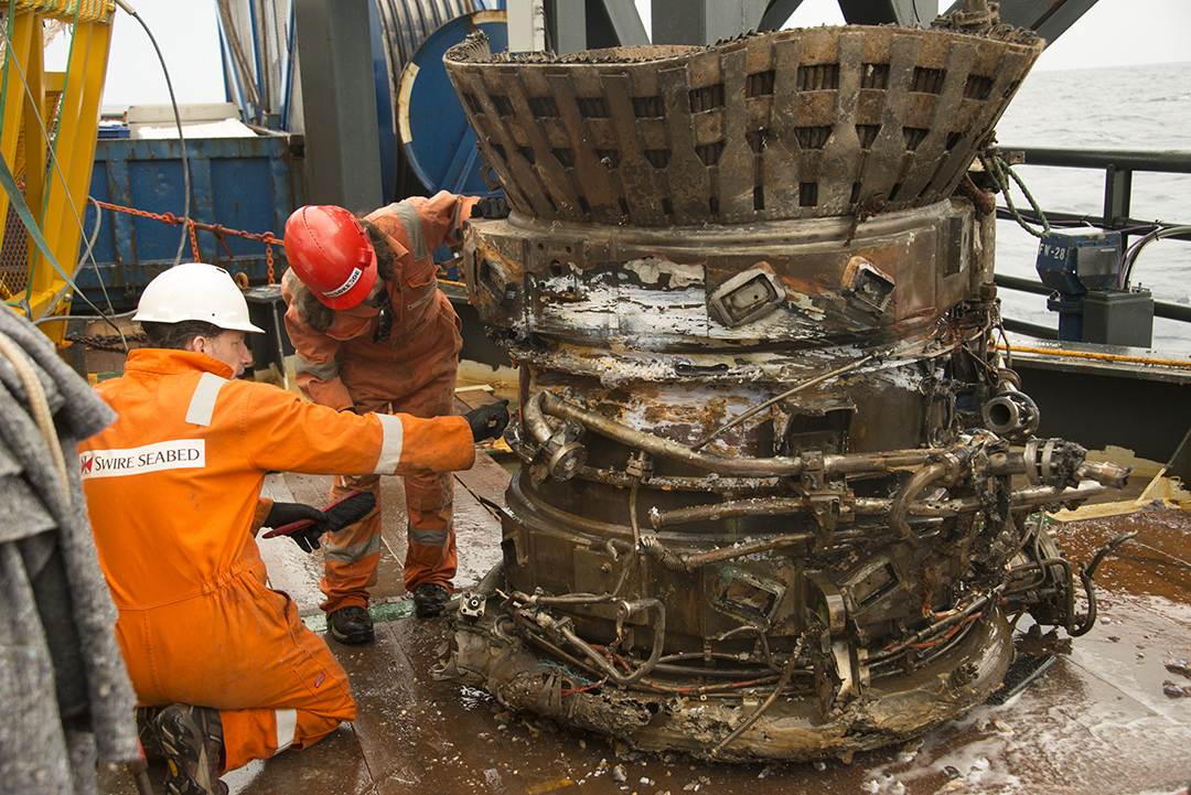Salvage workers check out the thrust chamber from an F-1 rocket engine aboard the Seabed Worker
