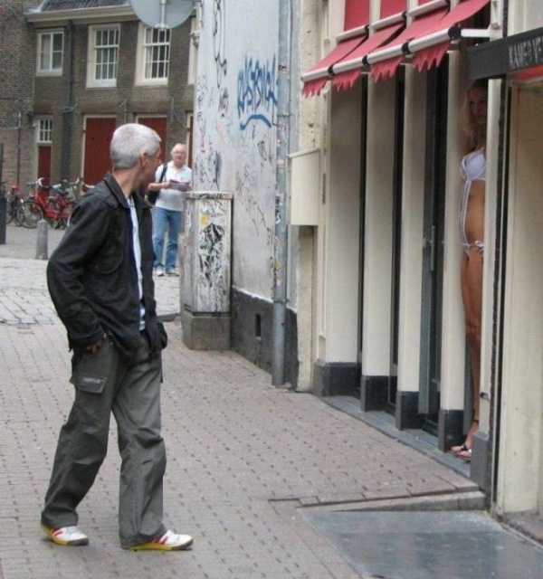 random picture of a john checking out a prostitute in a window of graffiti strewn streets