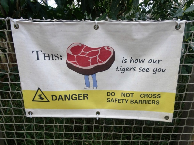 Warning sing in a zoo of how tiger's see you like a steak of meat