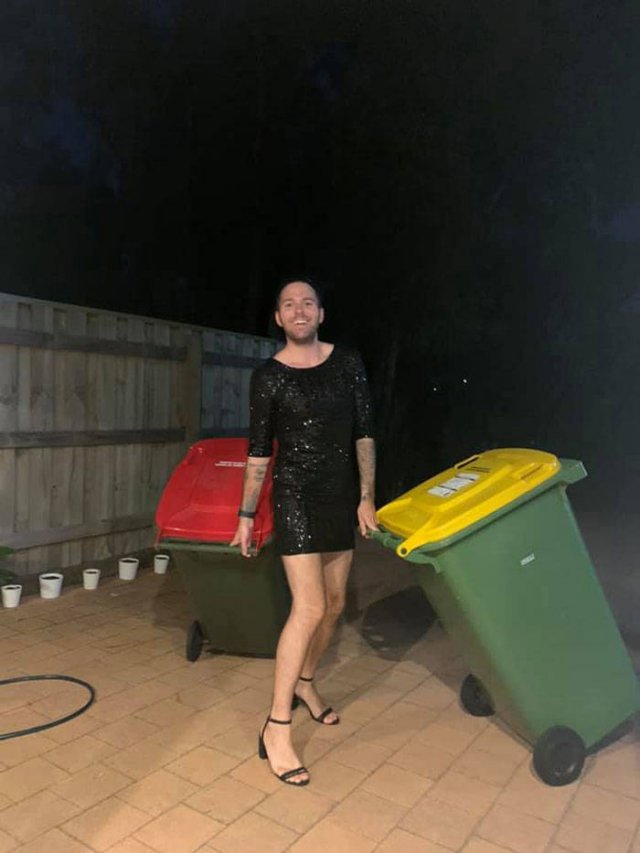 man wearing a dress taking out the trash