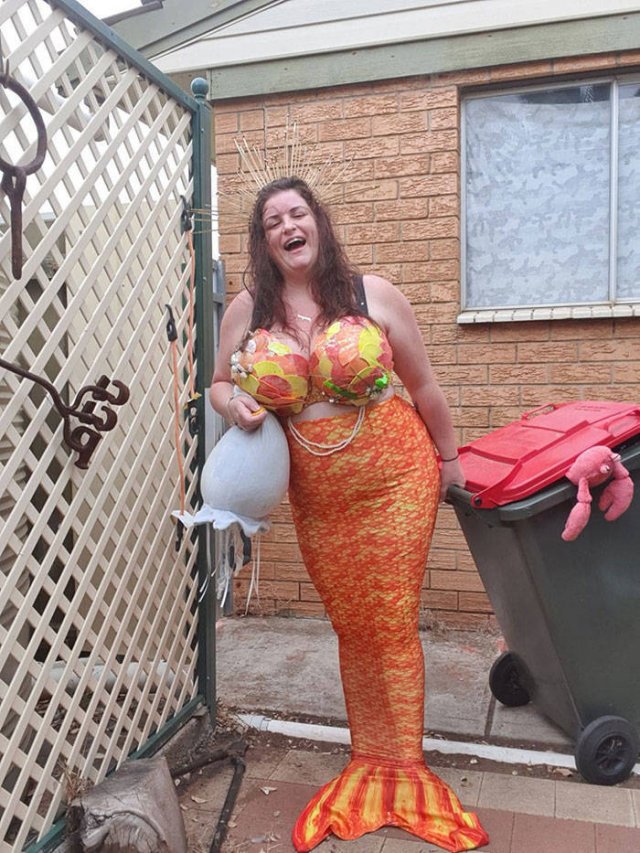 woman dressed as mermaid taking out the trash