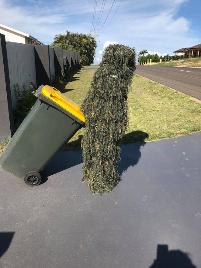 person covered in grass taking out the trash