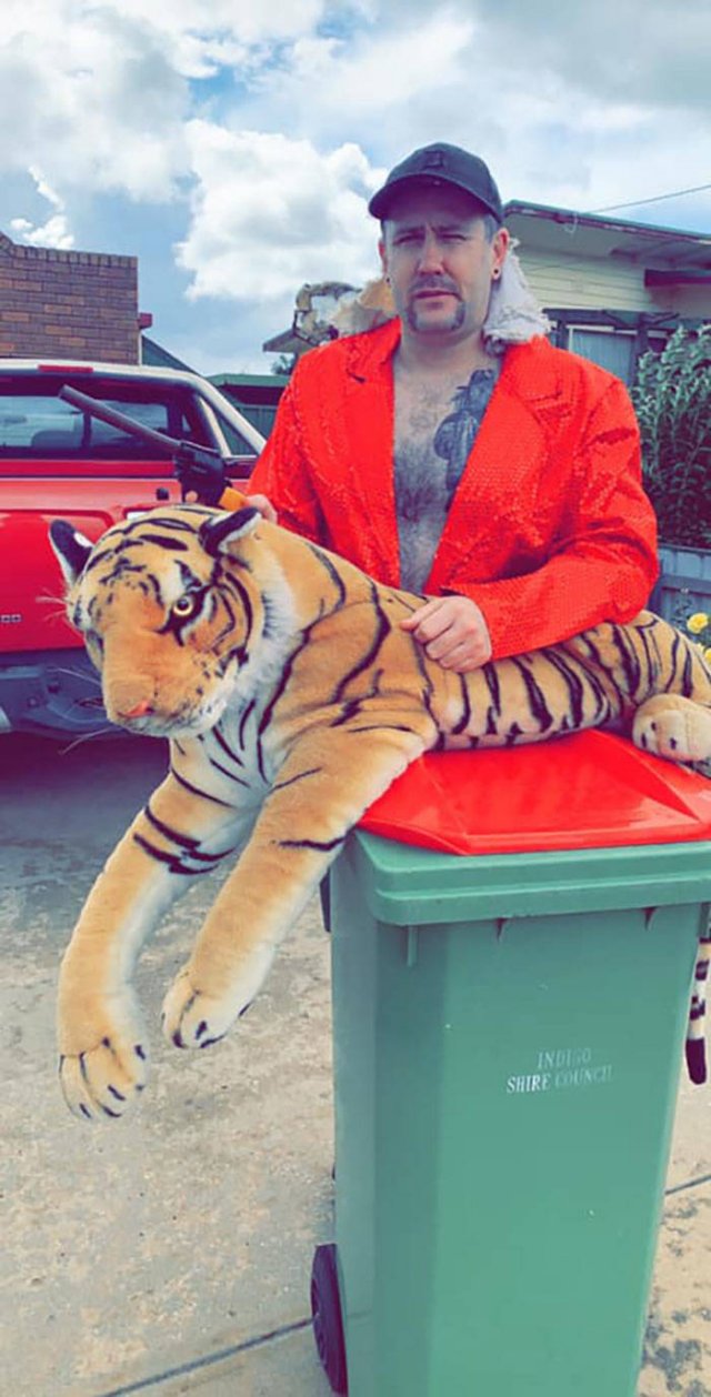 man with stuffed tiger dressed as joe exotic from tiger king with his trashcan