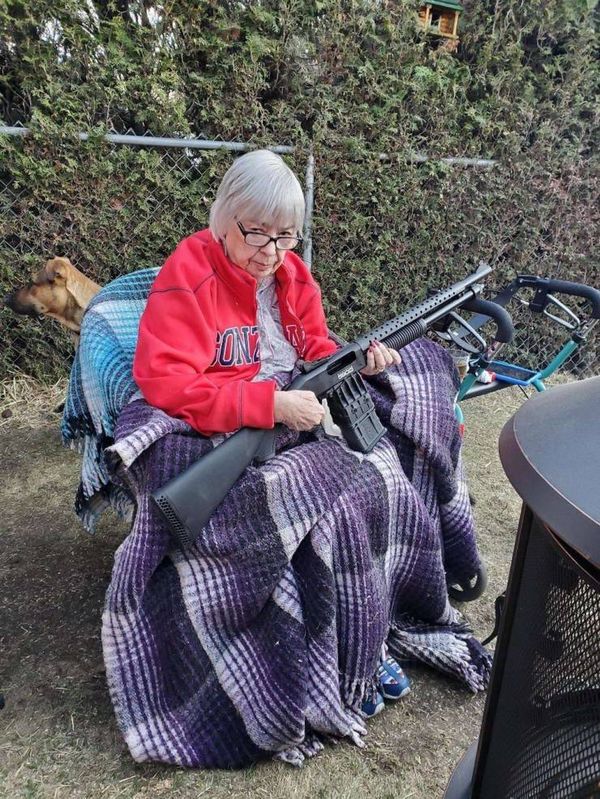 grandma sitting down holding a big shotgun