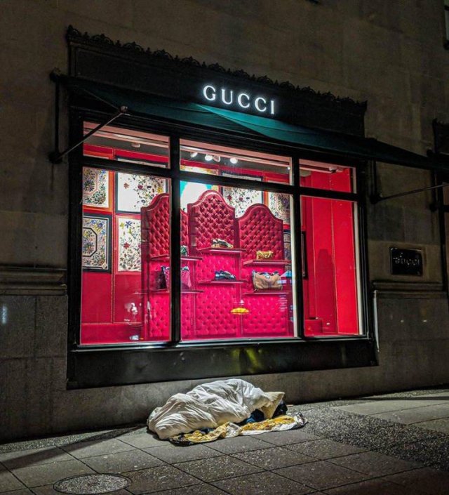 homeless person sleeping outside under gucci store window