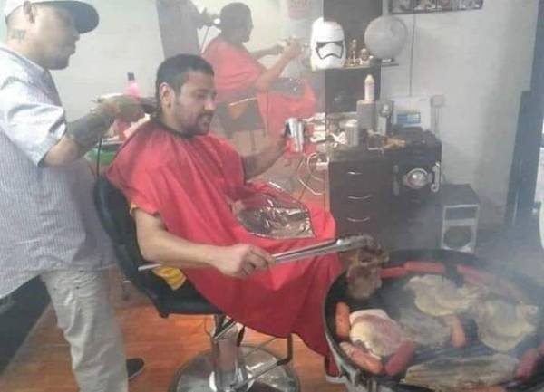 funny pictures - guy grilling meat indoors while getting his hair cut