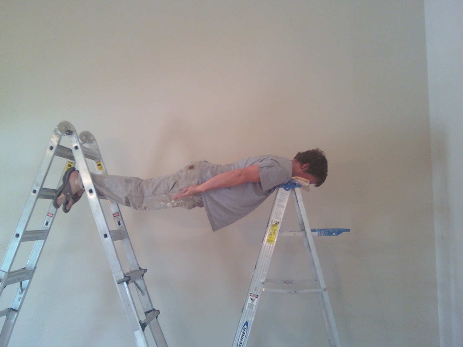 A painter planking on ladders.