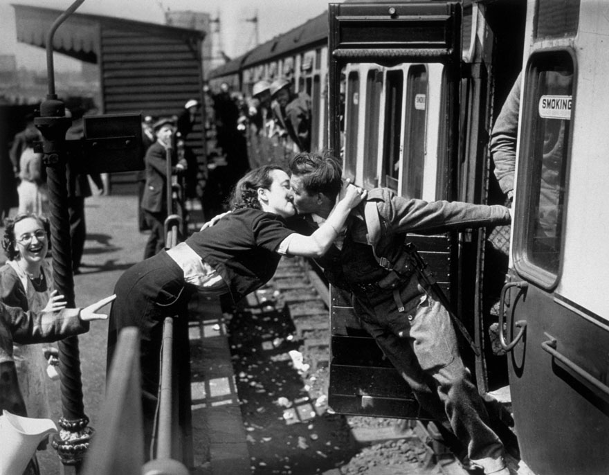 A Woman Leans Over The Railing To Kiss A British Soldier Returning From World War II, London, 1940