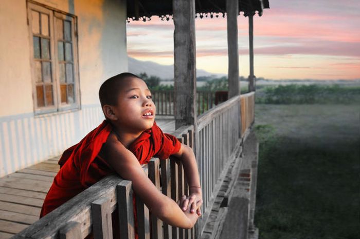 A little monk looks out over the scenic countryside from his monastery near Nyaungshwe, Burma.