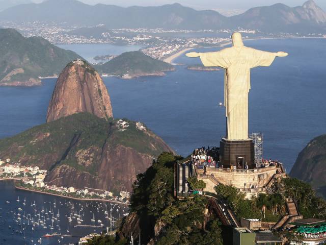 Pose with the massive statue of Christ the Redeemer on Corcovado Mountain in Rio de Janeiro, Brazil.