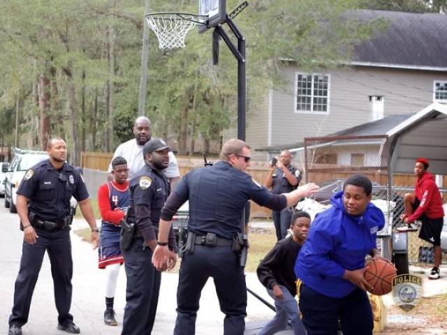 Shaq and officers playing basketball with children after reports of them playing too loudly.