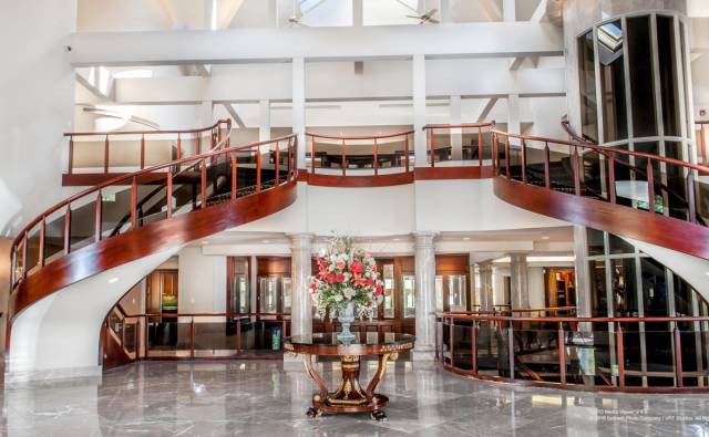 The mansion opens into a shining foyer with dueling, wood-paneled staircases.