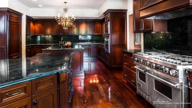 50's impressive kitchen is covered floor to wall with dark wood and green granite countertops and paneling.