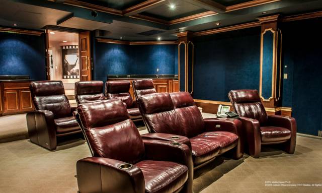 This luxurious home theater with blue velvet walls comfortably seats eight people in leather reclining chairs.