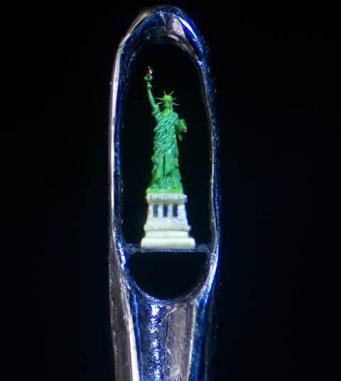 gold Statue of Liberty in the eye of a needle
