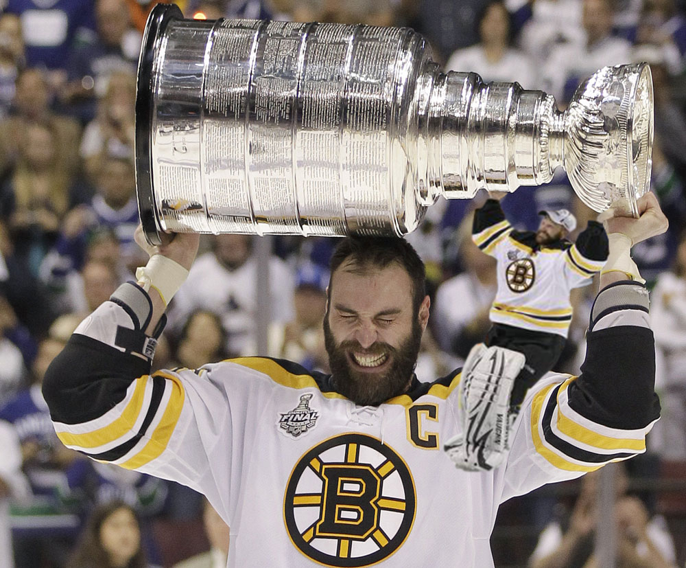 Tim Thomas helps the human giant, Zdeno Chara, hoist the Stanley Cup.  