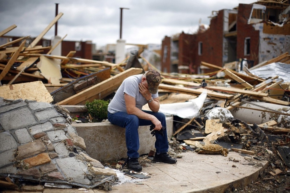 A man sits in front of a destroyed apartment building following the Joplin, Missouri tornado.