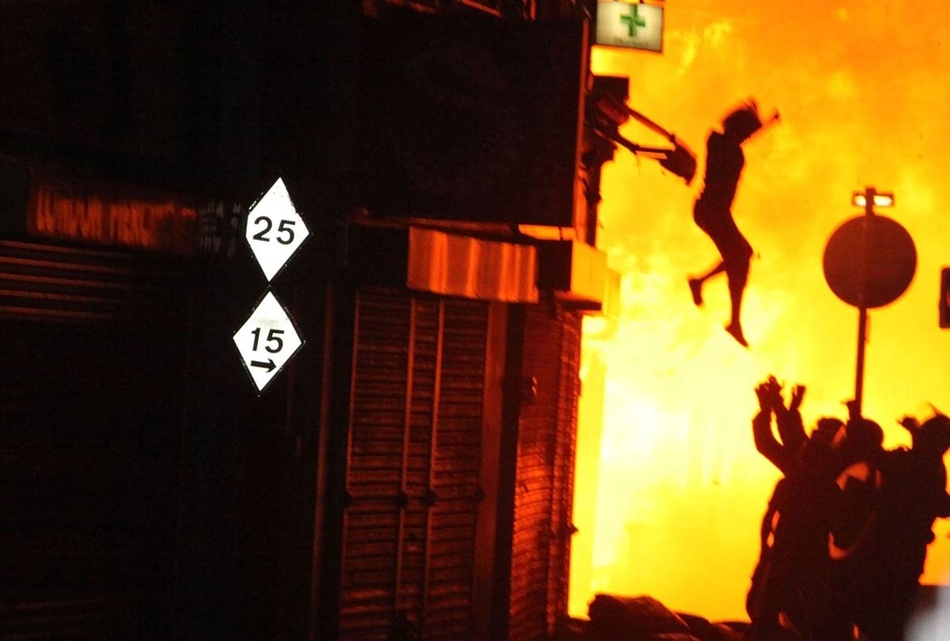 A woman jumps from a burning building during the London riots in August.