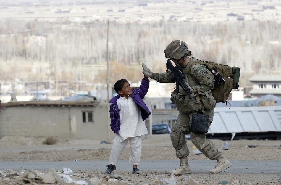 A U.S. Army soldier takes five with an Afghan boy.