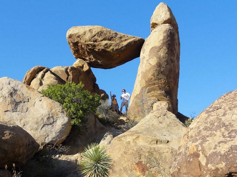 Couple standing next to odd shaped rock