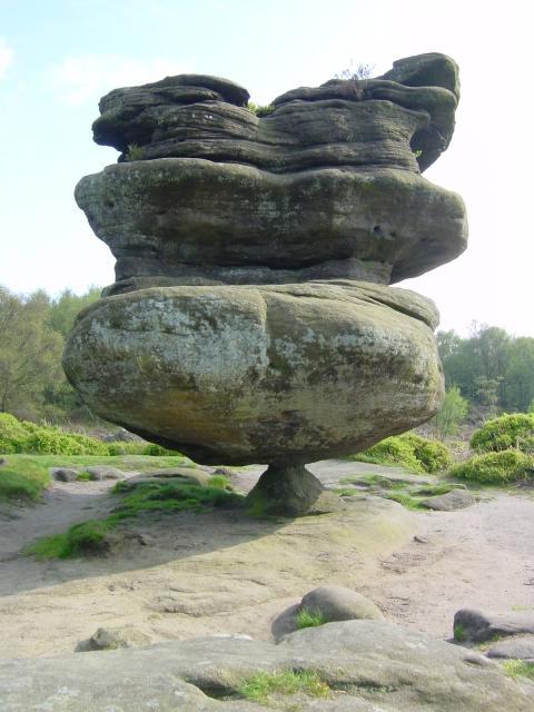 This balancing rock formation is one of the Brimham rocks, located on Brimham Moor in North Yorkshire, England. Made of millstone grit, it was carved over time through water and wind erosion. The bottom layer eroded fastest.
