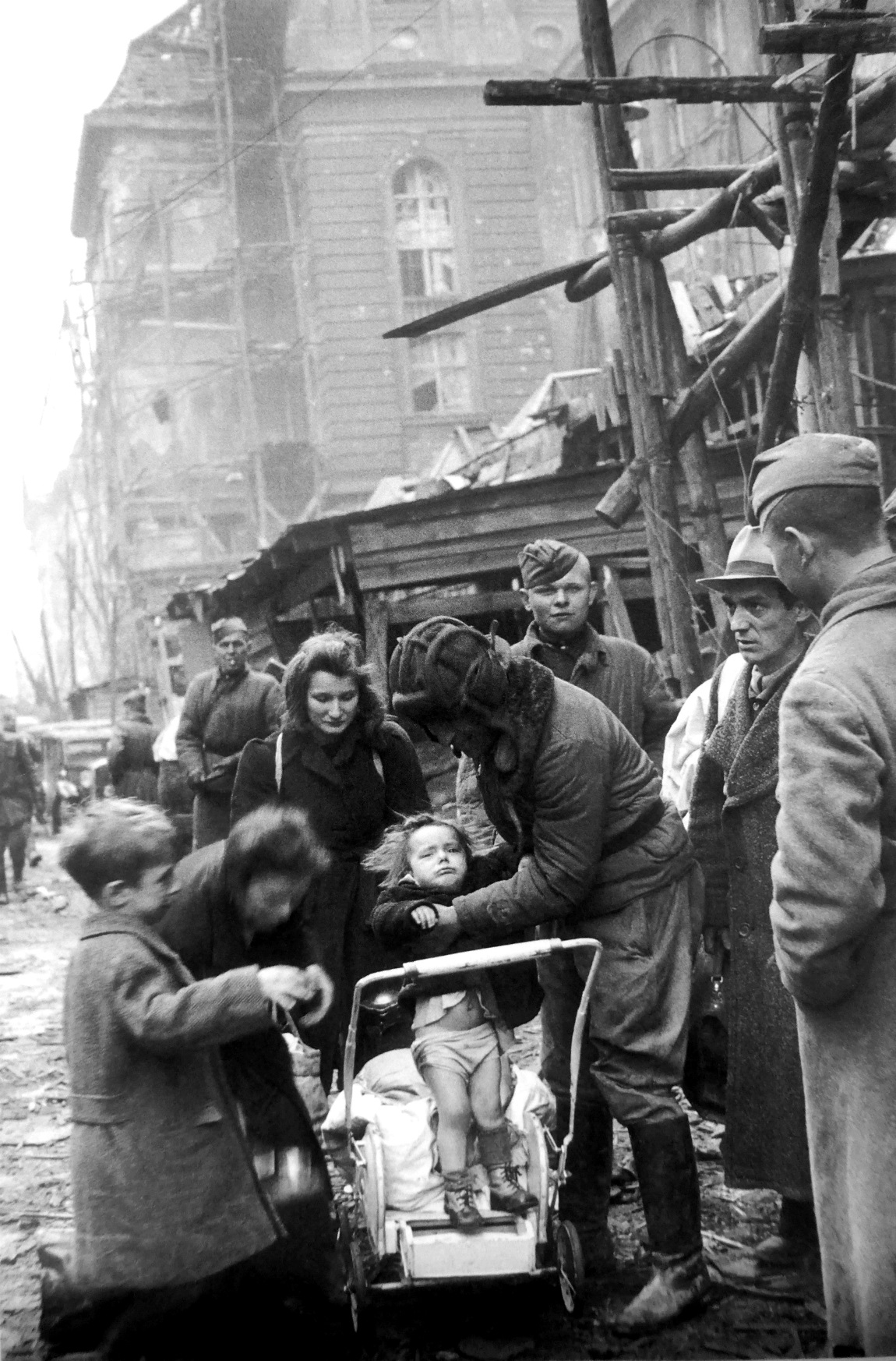 Soviet soldiers try to engage a less than cooperative German toddler for a photograph in the ruins of Monbijoustraße in defeated and Soviet occupied Berlin as the child’s mother looks on in resignation. May 1945