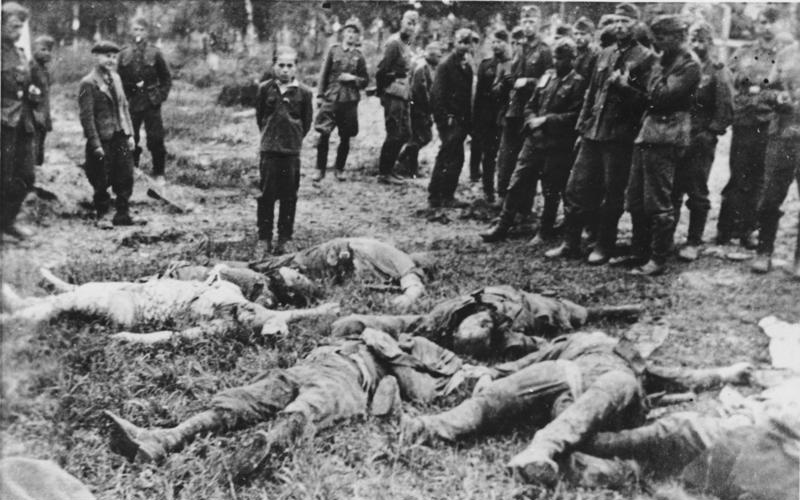 A boy is forced by SS members to view his murdered family and pose for a photograph before being murdered in Ukraine, 1941