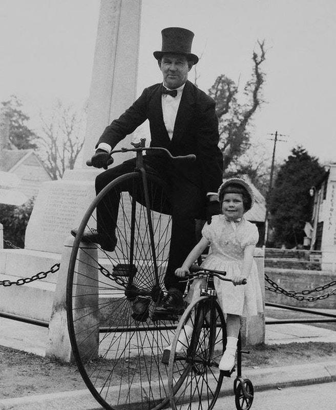 A father and his little girl riding on their penny-farthings in the 1930's