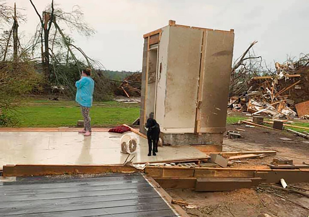 Amber Phillips stands outside the family’s safe room,  in Moss, Miss., following a tornado, Monday, April 13, 2020. While the rest of their home was destroyed in a matter of seconds Sunday, Phillips, her husband Andrew & their kids, ages 2 & 6 months, survived the storm without a scratch inside the small safe room, which doubles as a closet