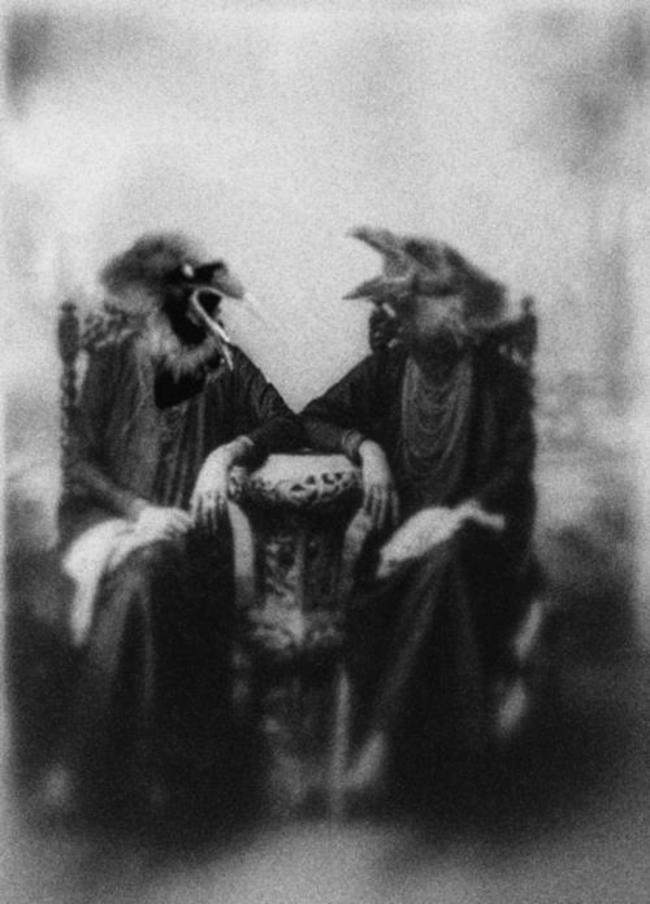 Two women wearing bird headdresses have a chat.